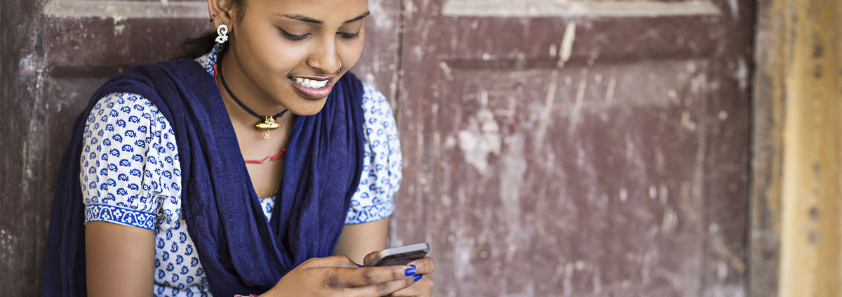 indian girl smiling sending a message on a mobile phone