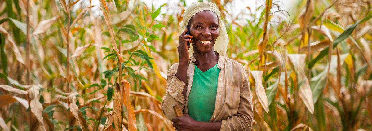 banner image, african woman holding cell phone smiling uganda article