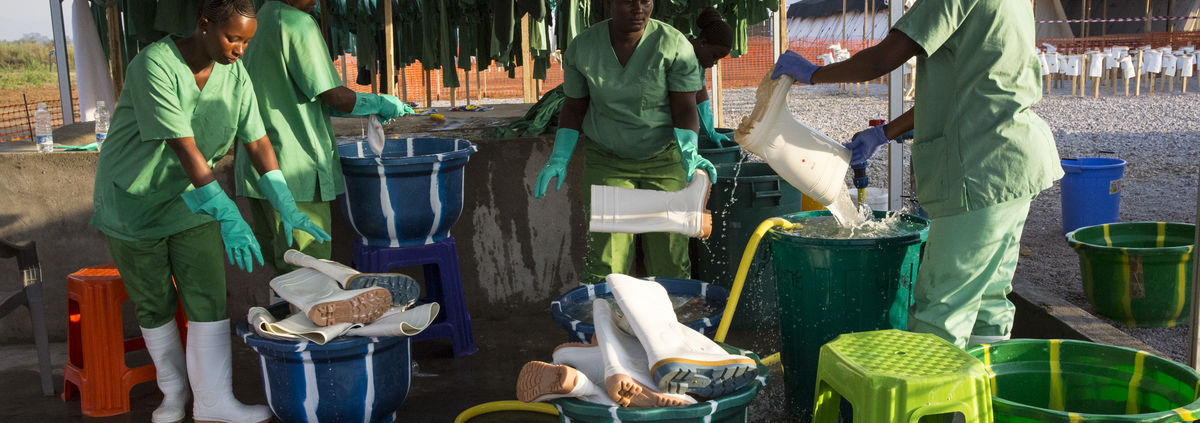 ebola women workers sterilizing boots