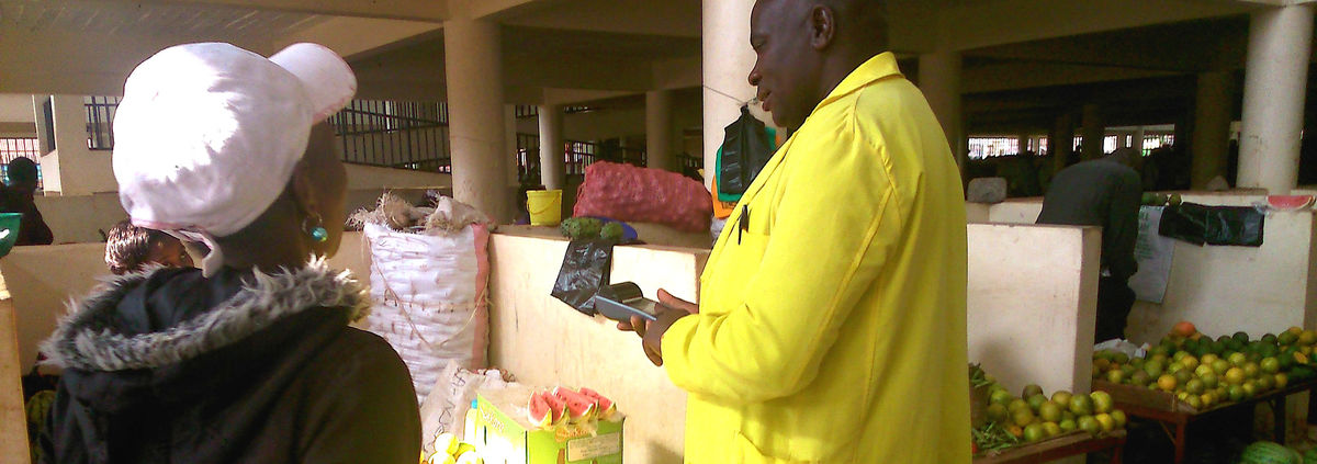 man in Ghana using mobile phone making digital payment at farmers market
