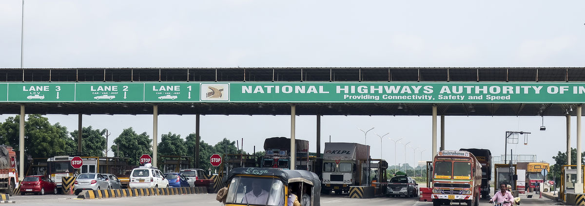 An autorickshaw comes out after paying a toll at a gate on the Bangalore-Hyderabad highway, India.